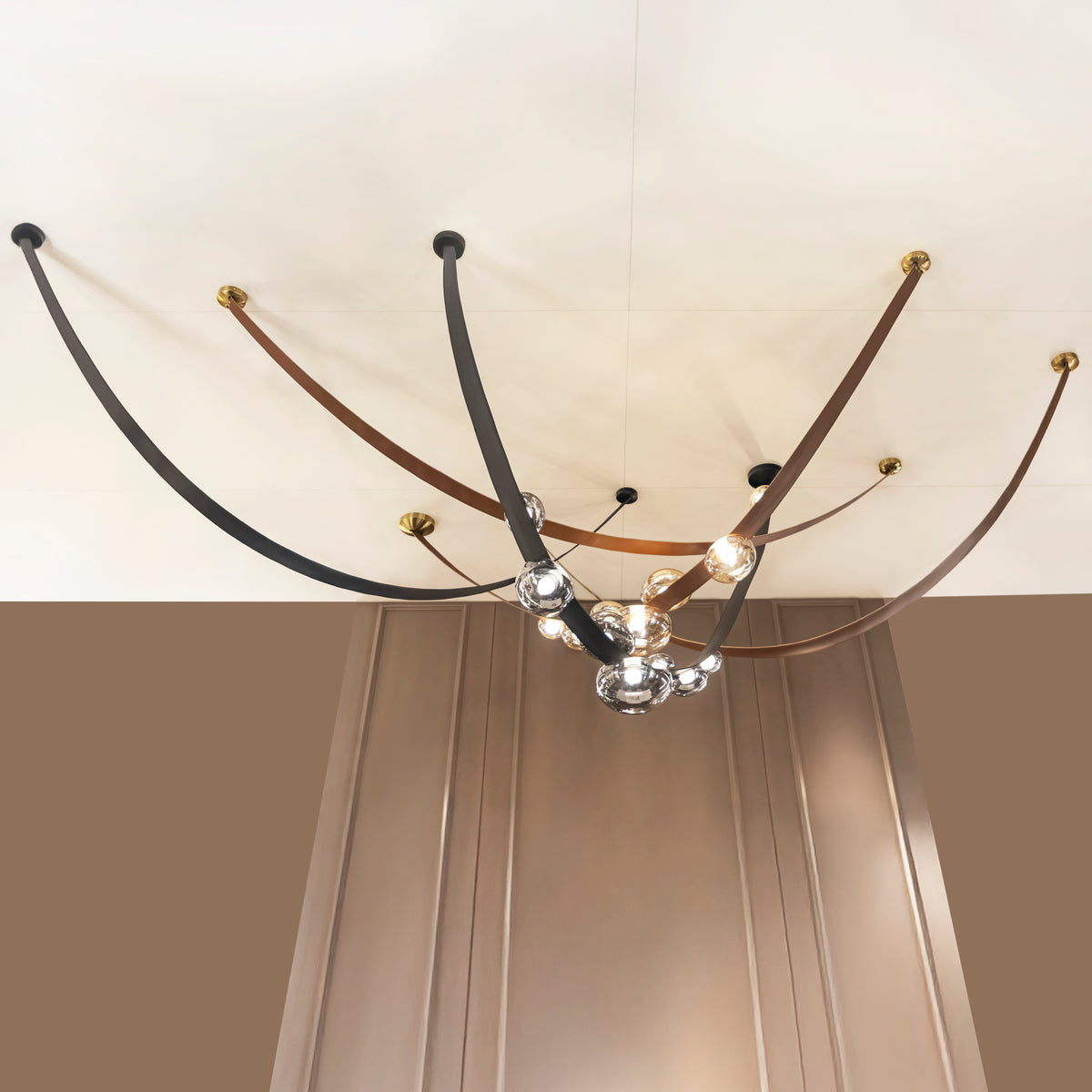 Modern chandelier with curved metal arms and glass shades on a ceiling.