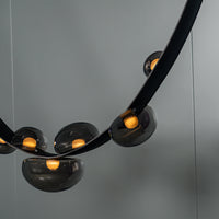 Modern black chandelier with gold bulbs on a gray background