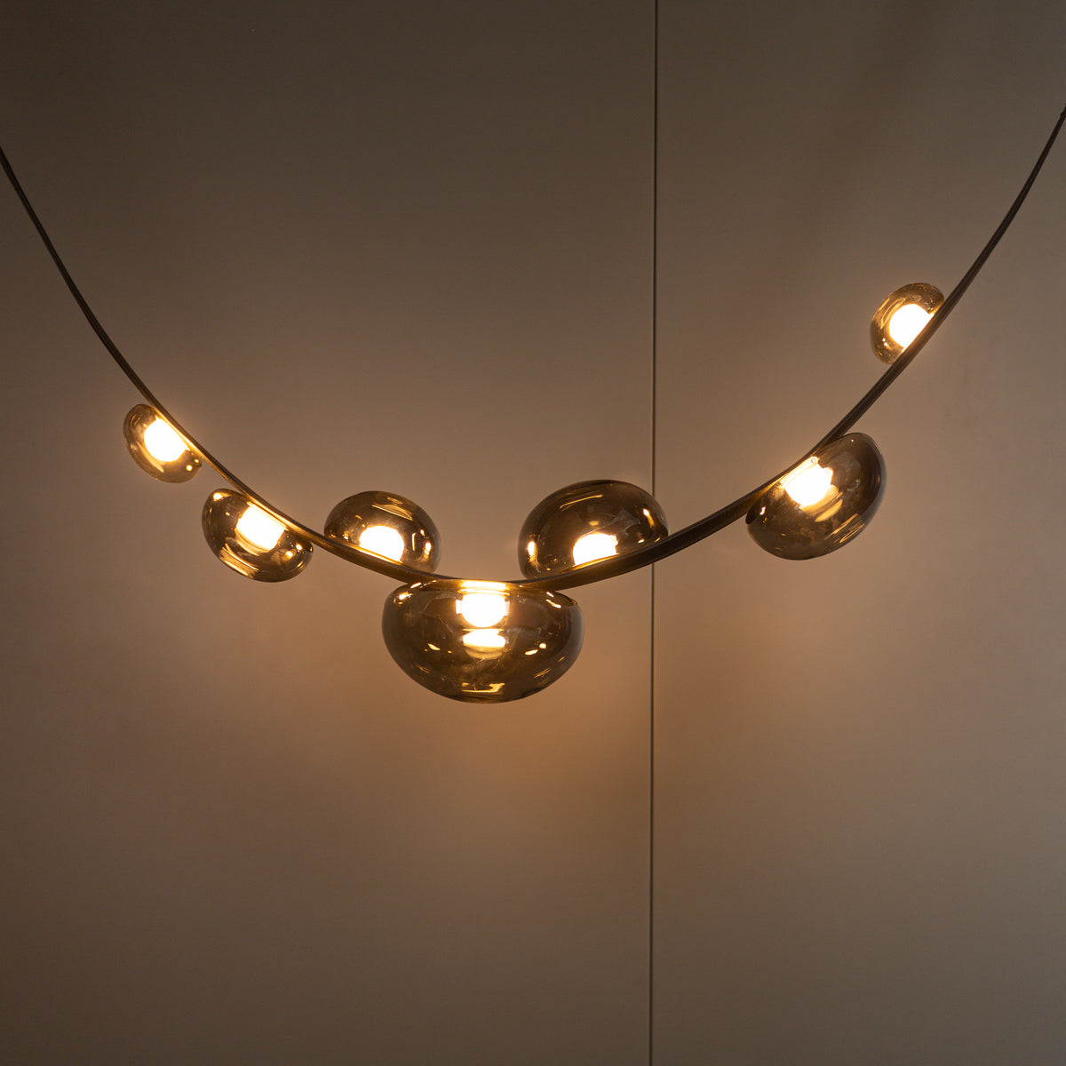 Modern chandelier with gold spherical lights on a neutral background