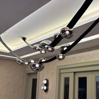 Modern chandelier hanging from a ceiling with a neutral wall and door in the background