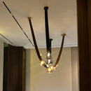 Modern chandelier with glass bulbs hanging from black metal rods against a neutral wall.