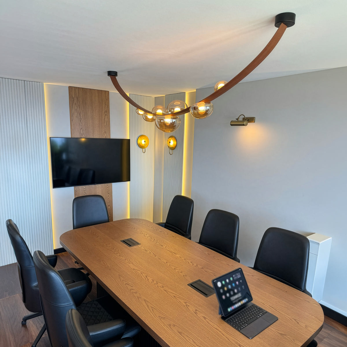Modern conference room with wooden table, chairs, and a TV.
