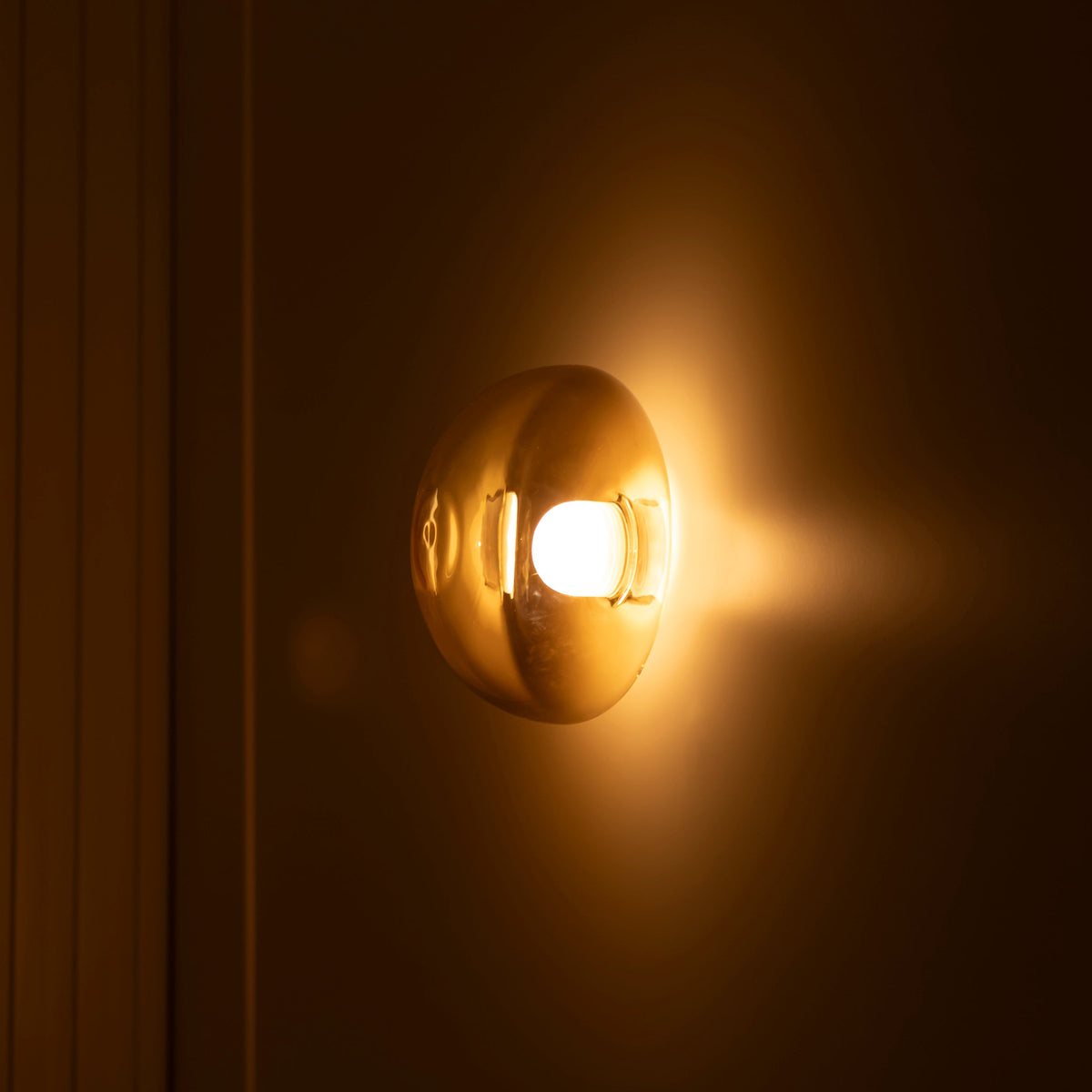 Gold wall sconce emitting warm light against a dark background