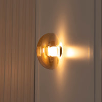 Gold wall sconce with a warm glow on a neutral background