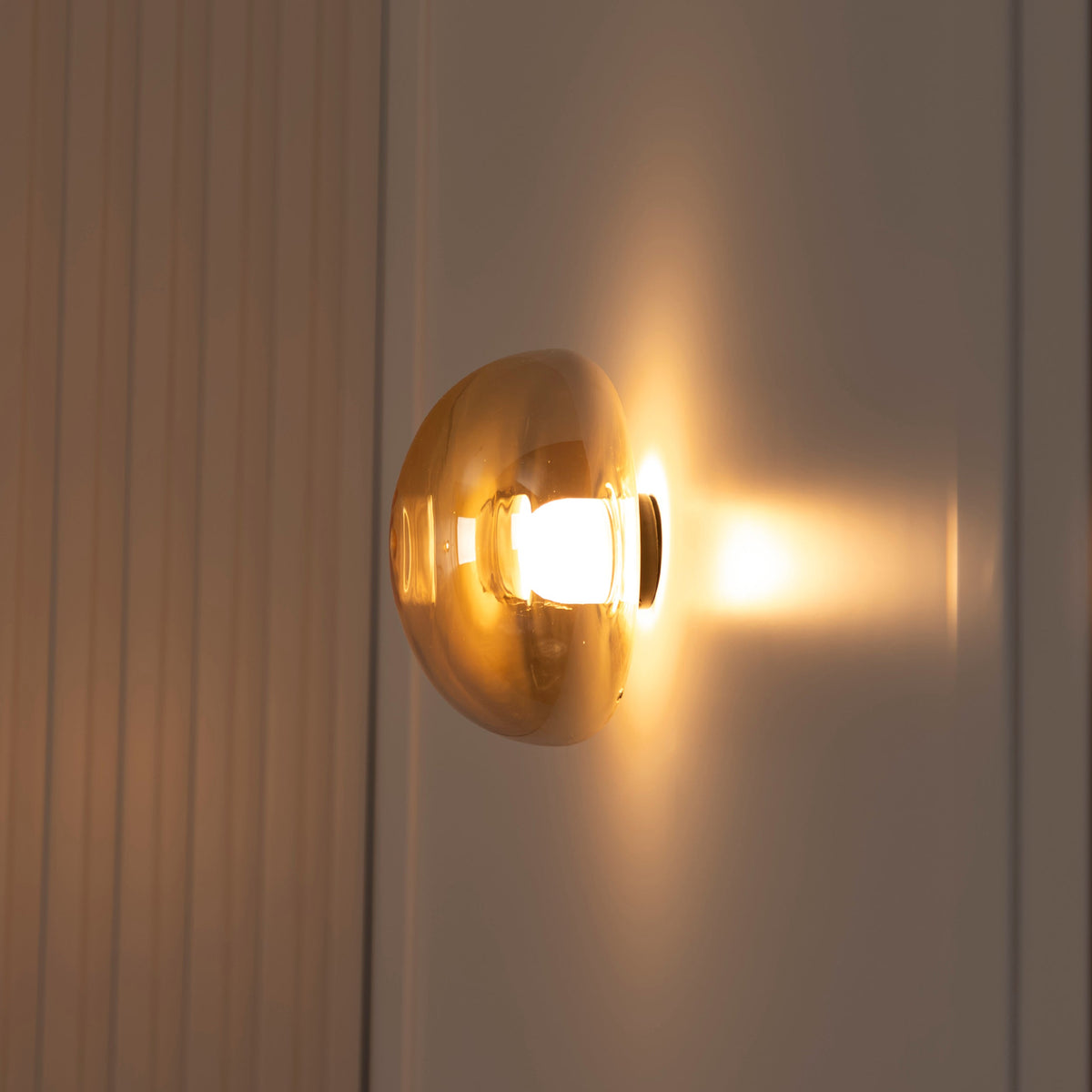 Gold wall sconce with a warm glow on a neutral background